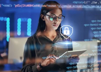 Mulher utiliza um tablet. A sua volta existem objetos adicionados digitalmente, incluindo um balão em forma de escudo com um cadeado dentro bem à sua frente. Falando sobre meios de comunicação na internet seguros.​