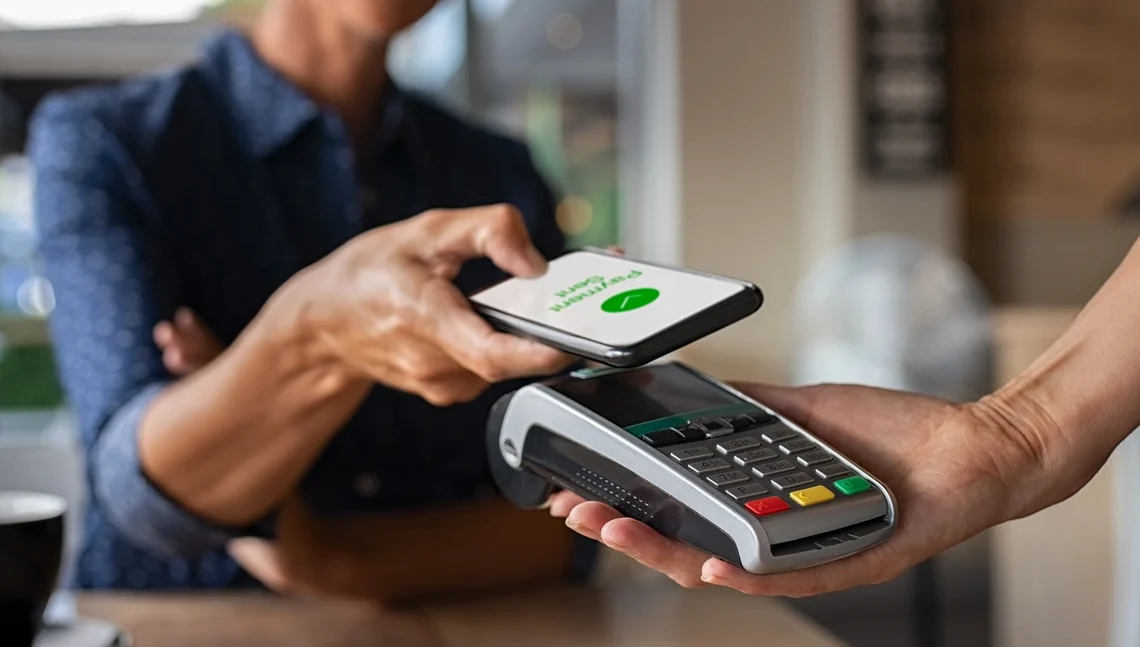 Homem faz pagamento utilizando o NFC do seu celular. Explicando o que é NFC em celular.