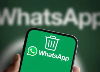 Pessoa segura smartphone com o símbolo do WhatsApp na tela. Acima dele, o símbolo de uma lixeira. Falando sobre como esvaziar a lixeira do whatsapp.